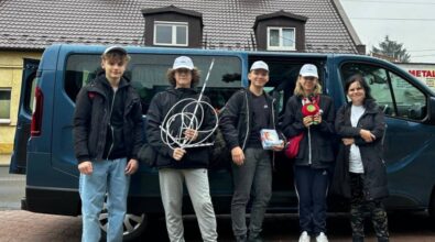 Członkowie Klub Młodego Odkrywcy MediaSat pozują do zdjęcia przed wyruszeniem do Warszawy. Stoją na tle ciemnego vana, niektórzy trzymają w rękach urządzenia i narzędzia potrzebne do eksperyment.
