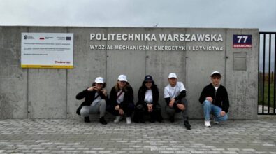 Członkowie Klub Młodego Odkrywcy MediaSat pozują do zdjęcia na tle betonowej ściany i napisu Politechnika Warszawska Wydział Mechaniczny Energetyki i Lotnictwa.