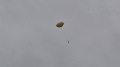 Widok z oddali na lecący w powietrzu balon meteorologiczny.