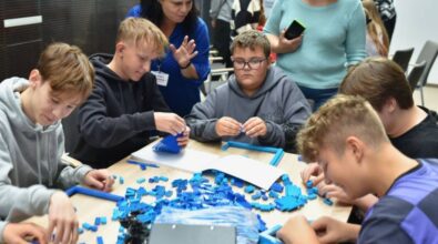 Uczestnicy budują konstrukcje z niebieskich klocków.