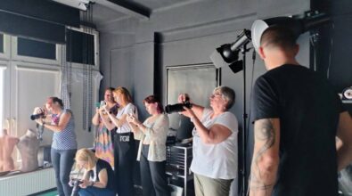 Zdjęcie przedstawia grupę ludzi w studio fotograficznym, skoncentrowanych na robieniu zdjęć.