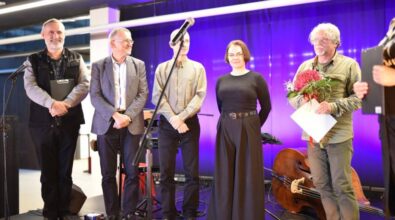 Grupka osób stoi na scenie. Wśród nich z bukietem hortensji laureat konkursu.