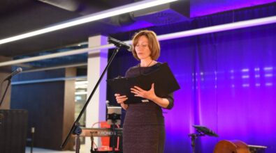 Laureatka nagrody za pierwsze miejsce stoi na scenie i czyta swój wiersz.