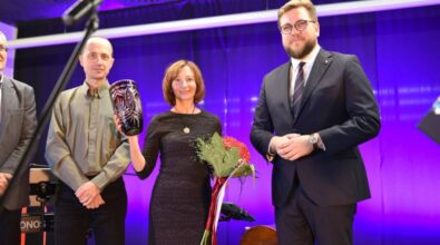 Laureatka konkursu stoi na scenie z prezydentem Piotrkowa Tryb. oraz osobami z jury. Wszyscy pozują do zdjęcia. Główna zwyciężczyni trzyma w rekach bukiet oraz rubinowy wazon.