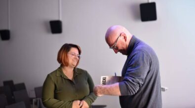 Gość wieczoru Rober Małecki podpisuje swoją książkę. Obok stoi uśmiechniętą kobieta.