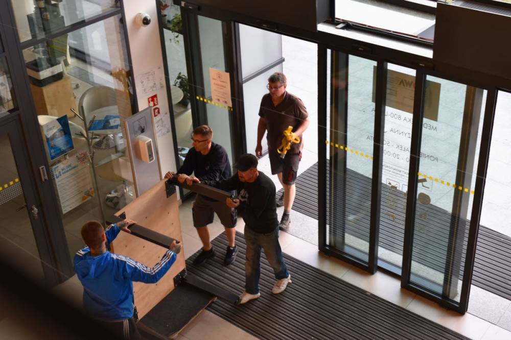 Grupa ludzi wnosi eksponat do Mediateki.