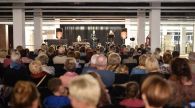 Zdjęcie z oddali ukazujące dużą część publiczności. W tle widać scenę z występującymi artystkami.