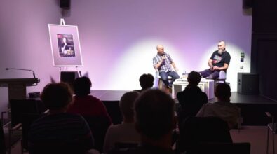 Rozmowa Piotra Milewskiego z prowadzącym spotkanie. Przed sceną siedzi publiczność, obserwując dyskusję.