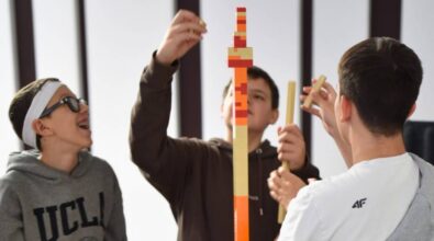 Uczestnicy budują wysoką piramidę w odcieniach pomarańczu, beżu i czerwieni.