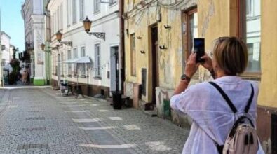Kobieta robi zdjęcia budynkom używając telefonu komórkowego.
