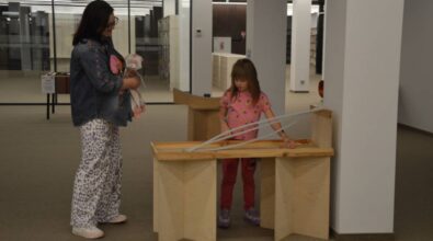 Kobieta z dzieckiem stoją przy jednym z eksponatów do eksperymentowania.