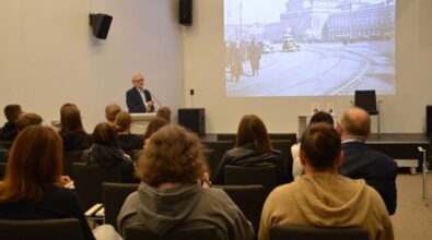 Autor przemawia do publiczności. Na ekranie slajd z prezentacji o historii kostki Rubika..