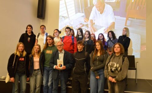 Autor książki pozuje do zdjęcia z grupa uczniów, którzy przyszli na spotkanie.