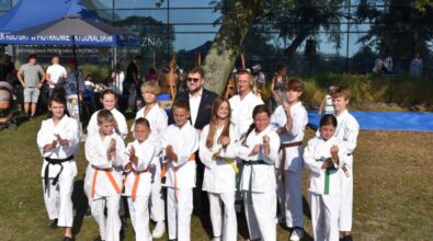 Na zdjęciu widzimy grupę dzieci w strojach do karate pozujących do zdjęcia razem z prezydentem miasta. W tle widać namioty i budynek Mediateki