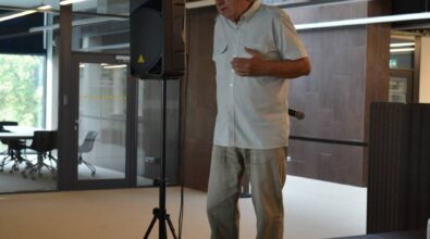 Jerzy Rogalski stoi na scenie. Ubrany jest w jasną koszulę z krótkim rękawem i jasne spodnie. Cała scena ma miejsce w pomieszczeniu. Po prawej stronie mężczyzny stoi głośnik. Zdjęcie własnością MBP.