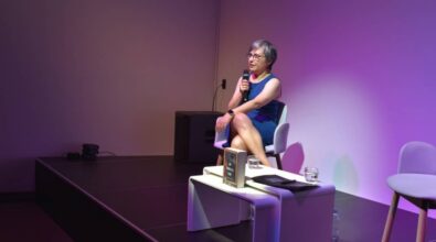 Na scenie siedzi Agnieszka Gehrke i przemawia do mikrofonu.