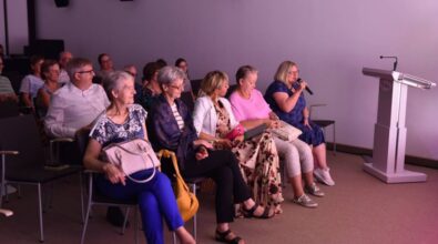 Zdjęcie publiczności. Jedna osoba trzyma mikrofon i zadaje pytania.