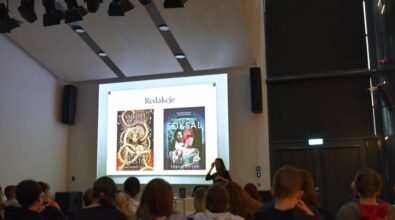 Widok na kolejny slajd prezentacji, osobę prowadzącą oraz publiczność.