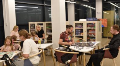 Widok na osoby siedzące przy stolikach i grające w gry planszowe.