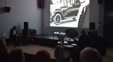 Sala kinowa. Przed ekranem mężczyźni grający na instrumentach.