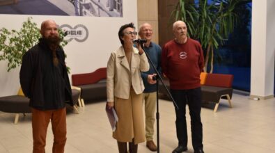 Dyrektorka Miejskiej Biblioteki przemawia do mikrofonu. Za nią stoi trzech artystów malarzy.