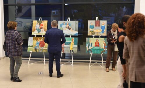 Uczestnicy wystawy oglądają obrazy.