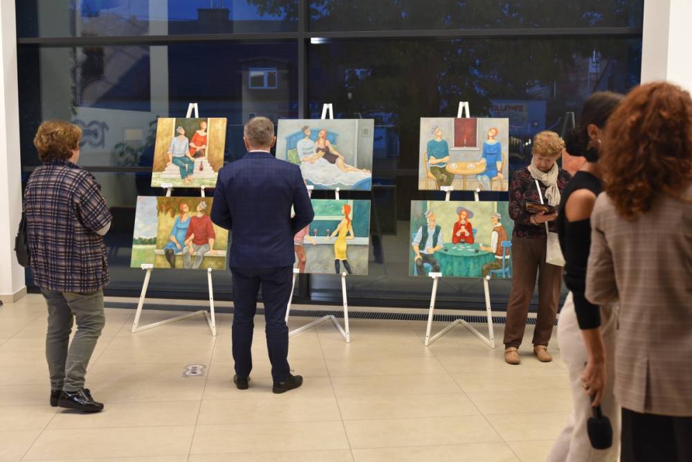 Uczestnicy wystawy oglądają obrazy.