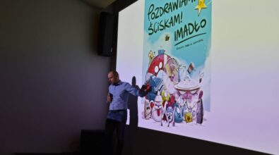 Prowadzący wskazuje na ekran gdzie widać zdjęcie książki pod tytułem 