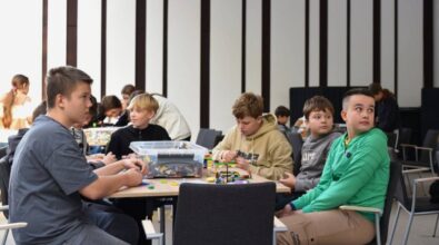 Uczniowie siedzą przy stolikach i budują konstrukcje.