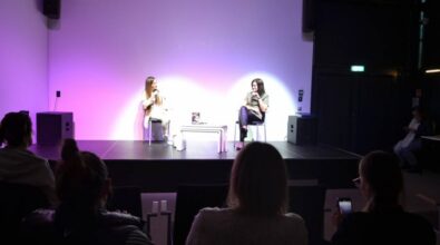 Kolejny kadr na scenę, ukazujący rozmawiające kobiety wraz z osobami na widowni.