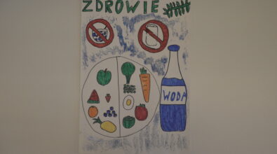 Praca konkursowa w formie plakatu przedstawiająca podzielony na 2 części talerz z warzywami, owocami i jajkiem. Po prawej stronie butelka wody. Na górze przekreślona sól i cukier oraz zielony napis „ZDROWIE”. Praca wykonana mazakami. Tło białe z niebieskim brokatem.